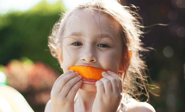 child with diabetes eating orange